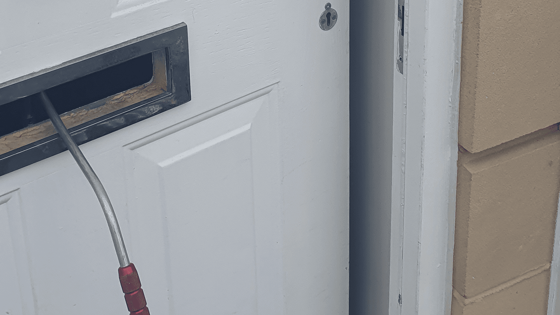 The front door with the letter box access bar tool in place and door now open
